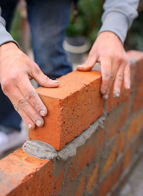 A man is building a brick wall with his hands.