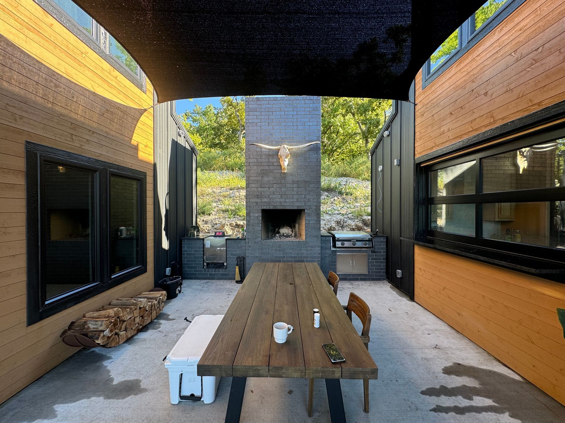 A patio with a wooden table and chairs and a fireplace.