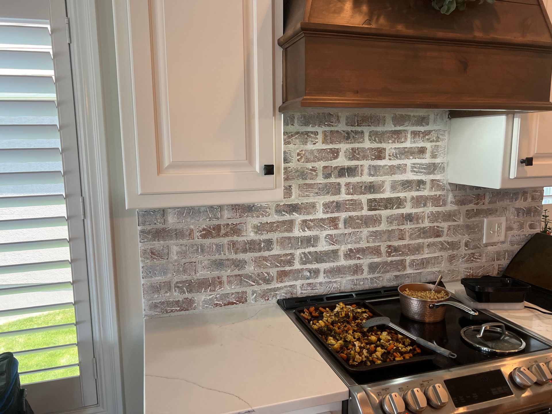 A kitchen with a stove top oven and a copper hood.