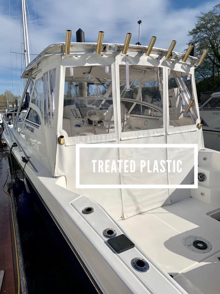 White boat with treated plastic enclosure at a dock.