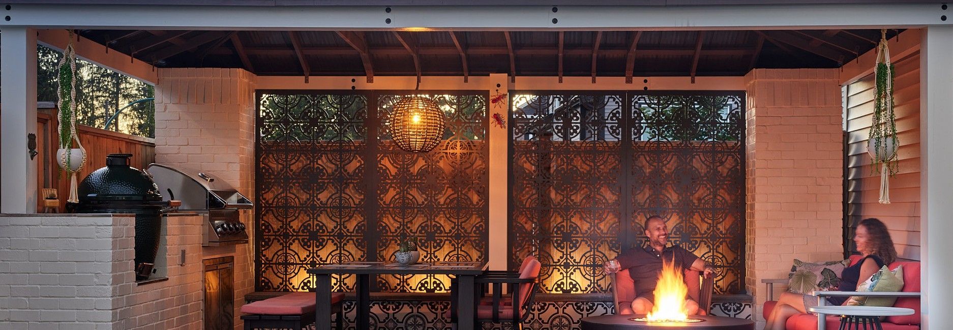 Cozy outdoor living space with fire pit, seating, decorative screens, and a woman relaxing.