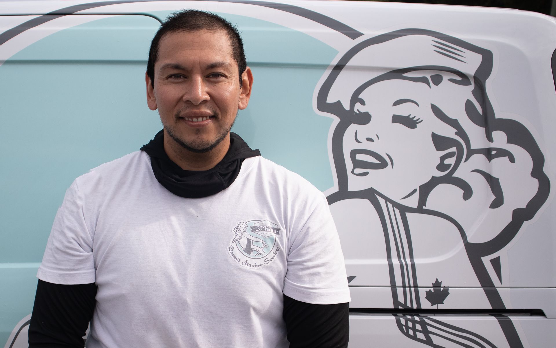 Man in white shirt stands next to a van with a graphic of a smiling woman.