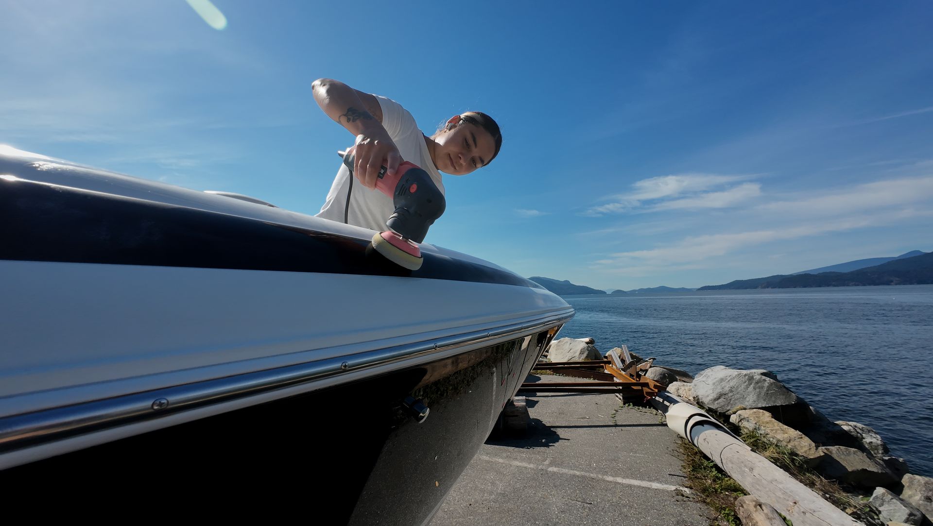 Person leaning over boat, ocean background. Bright blue sky.