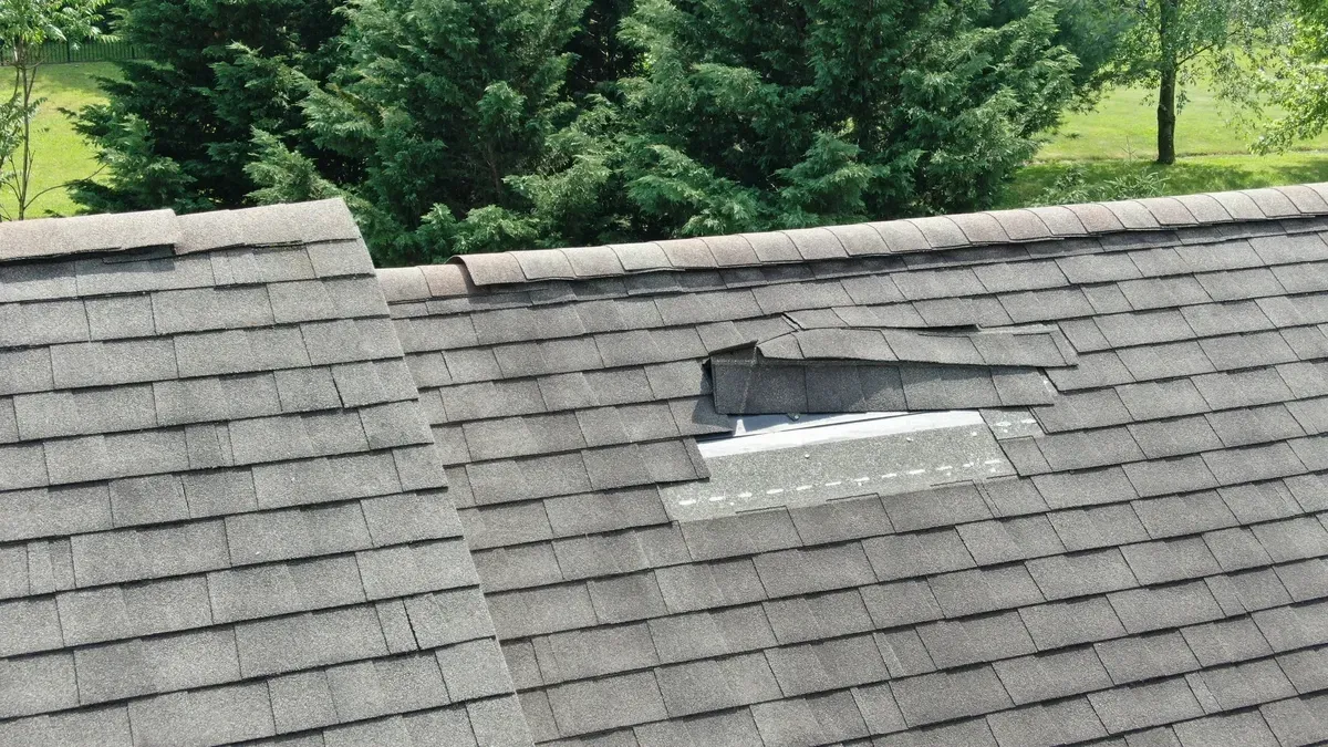 Damaged roof with missing shingles exposing underlayment.