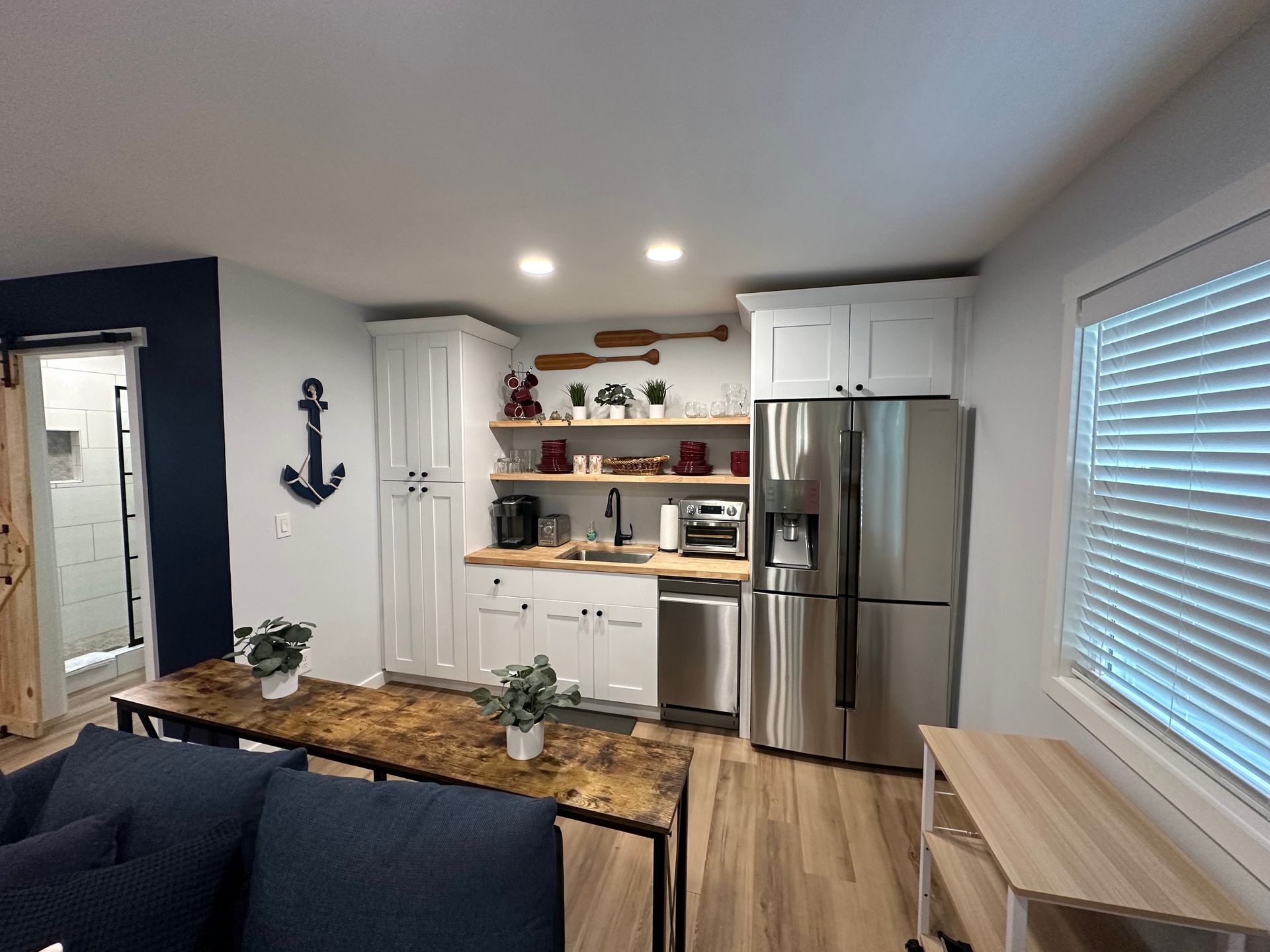 A living room with a couch , table , refrigerator and sink.