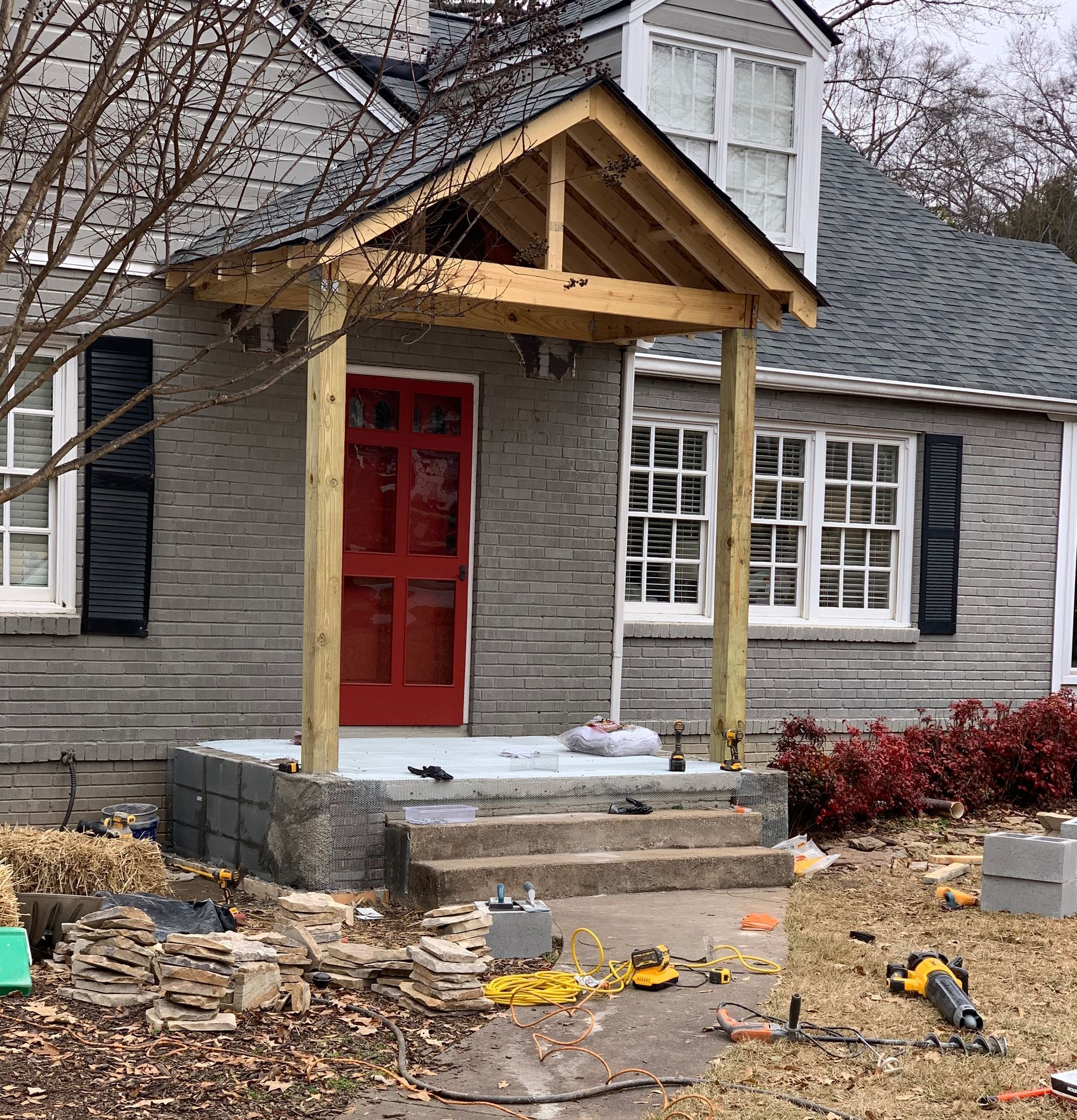 A house with a porch and a red door is being remodeled.