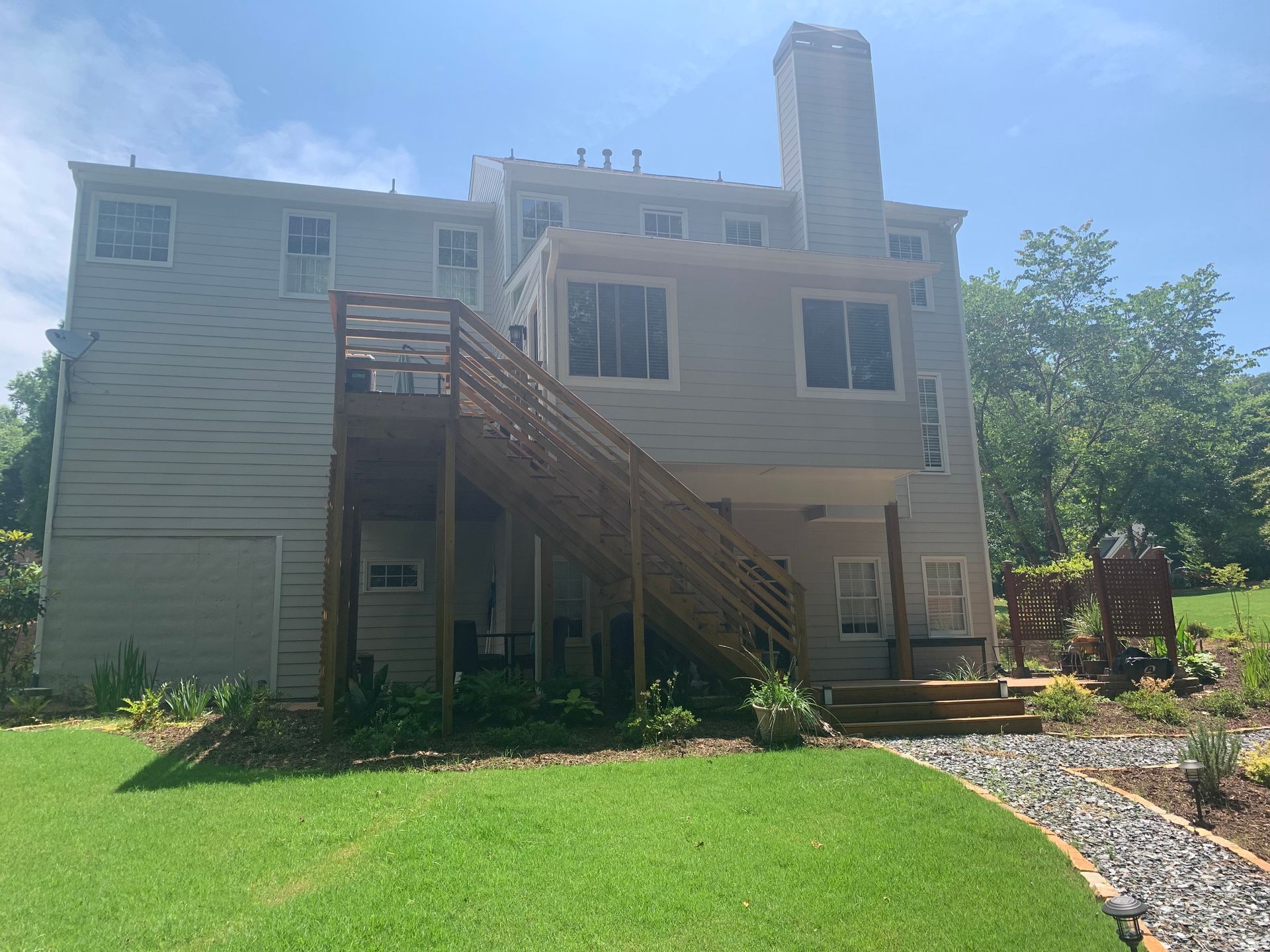 The back of a large house with a deck and stairs.