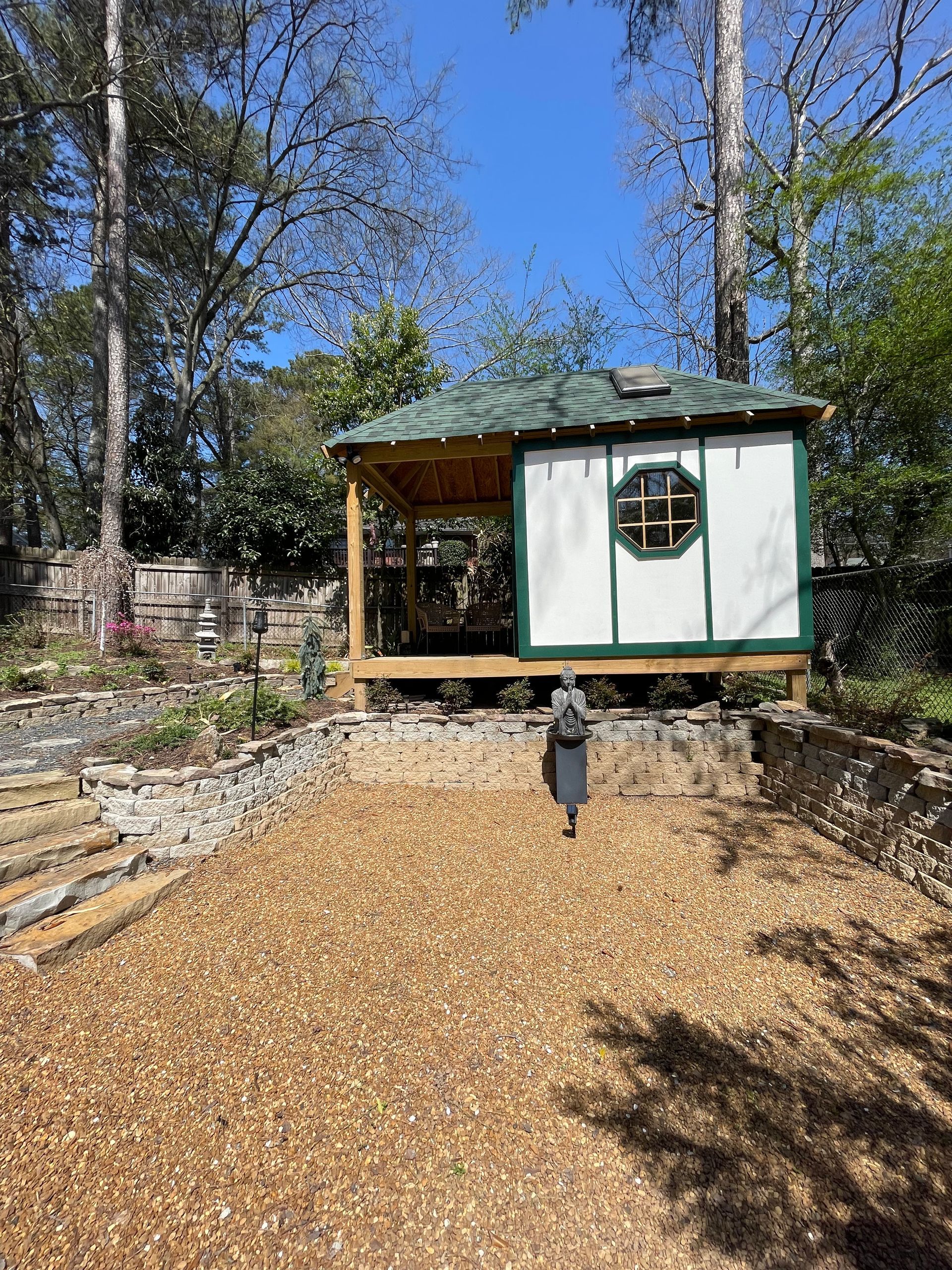 A person is walking towards a gazebo in the woods.