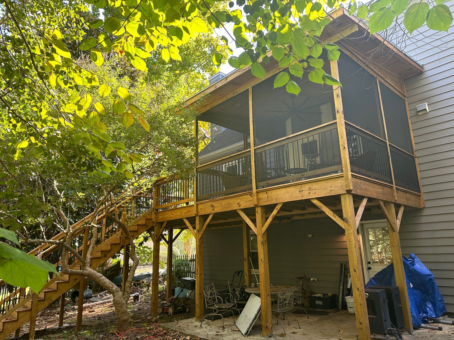 A screened in porch with stairs leading up to it and a house in the background.