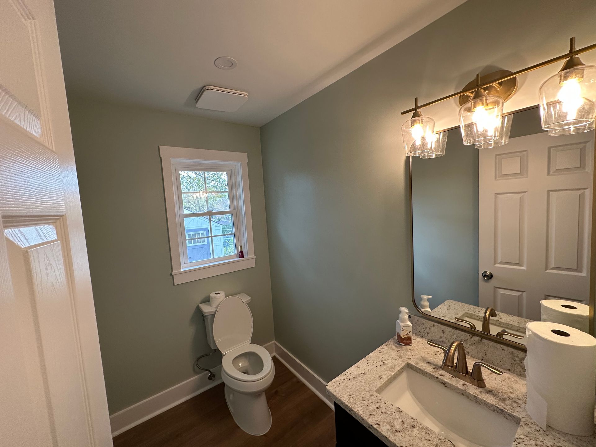 A bathroom with a toilet , sink and mirror.