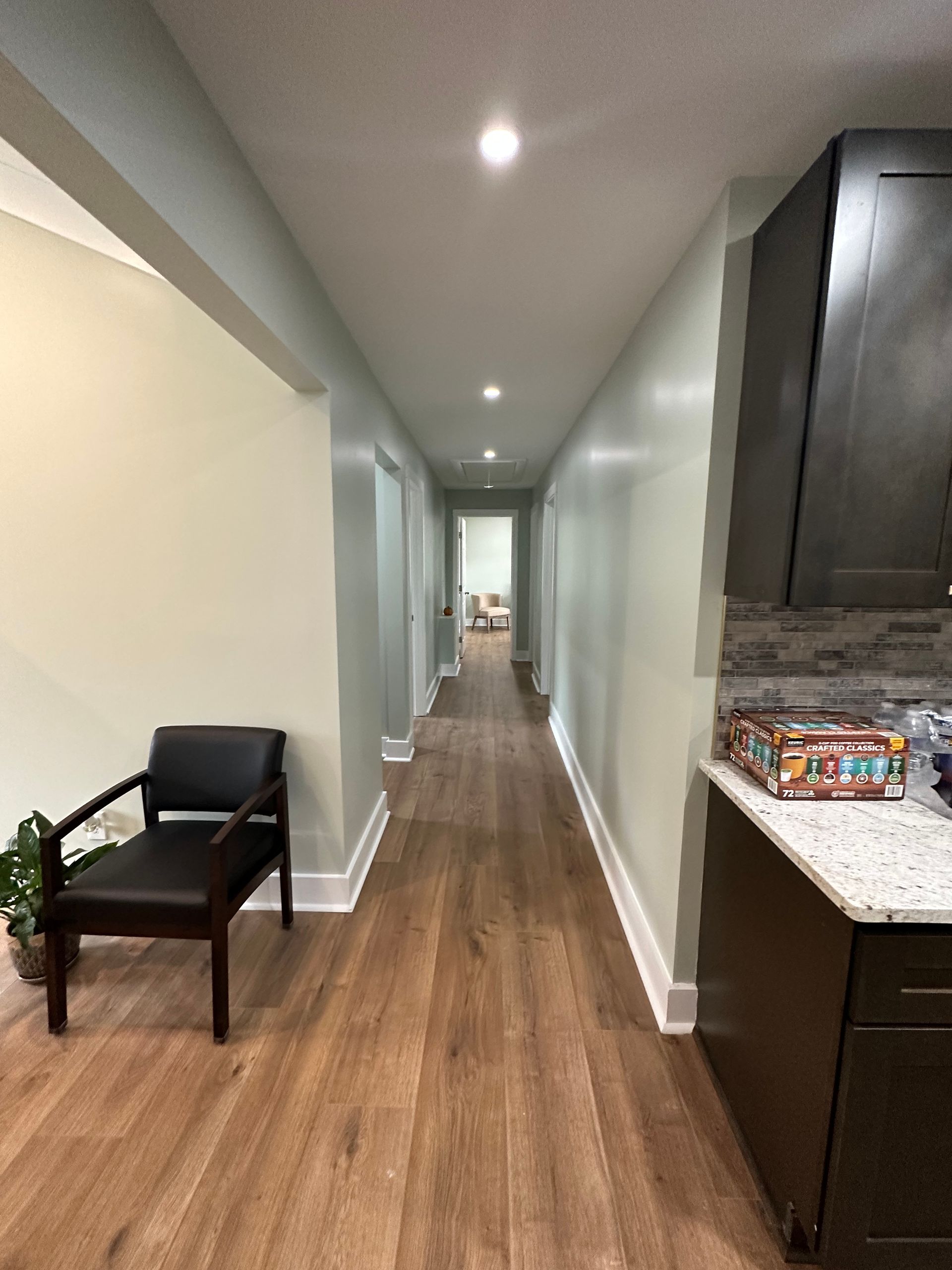 A long hallway with wooden floors and a chair in the middle