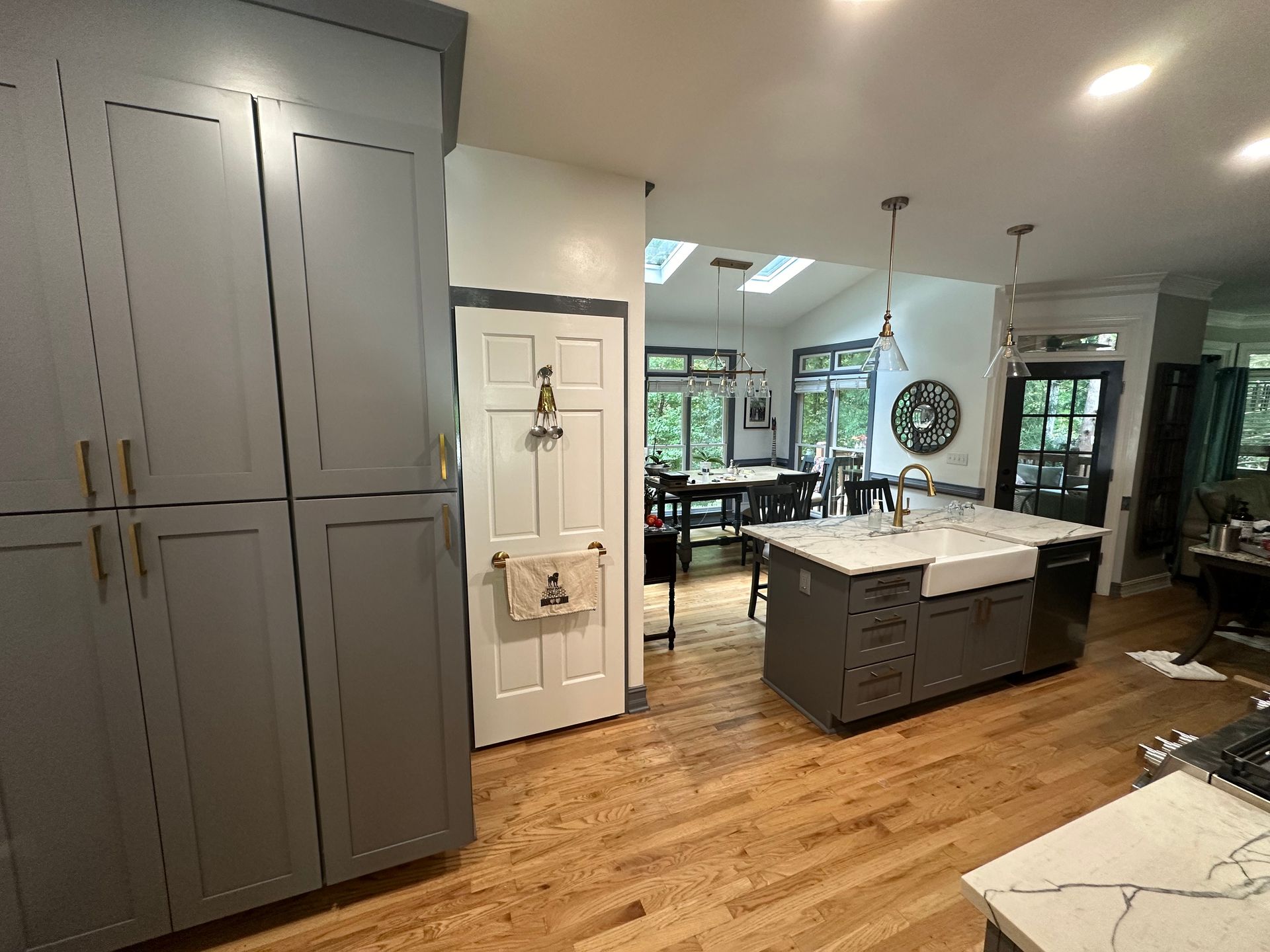 A kitchen with gray cabinets , a white sink , and a large island.