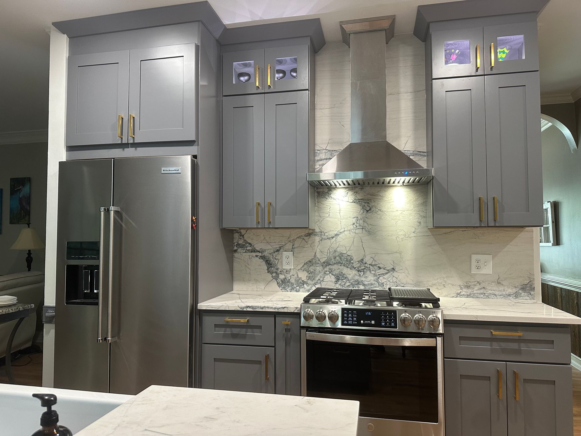 A kitchen with stainless steel appliances and gray cabinets.