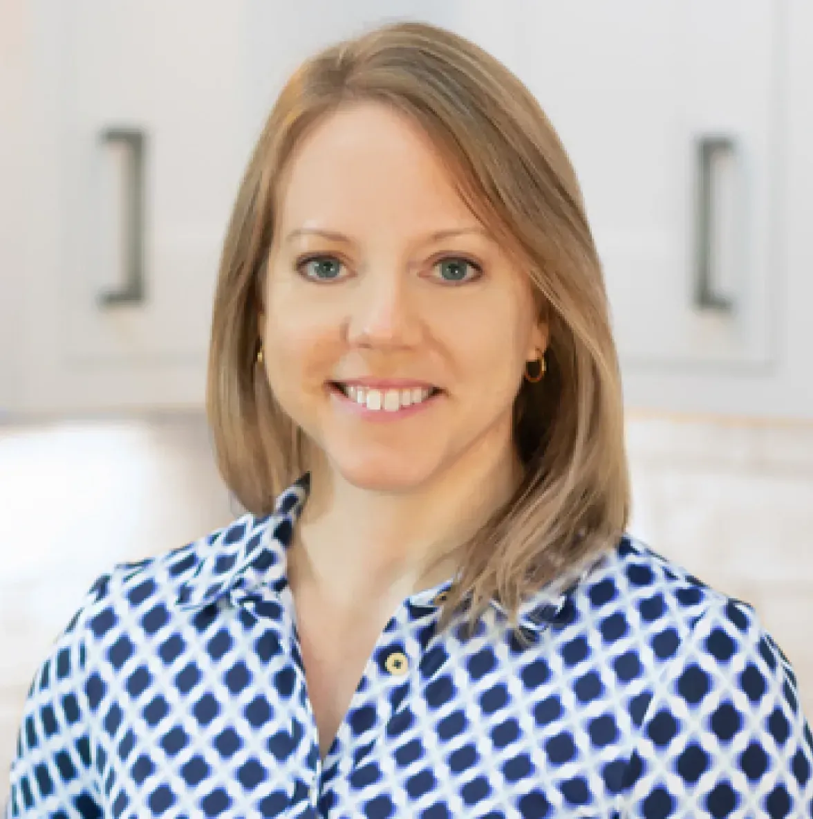 A woman in a blue and white shirt is smiling for the camera.