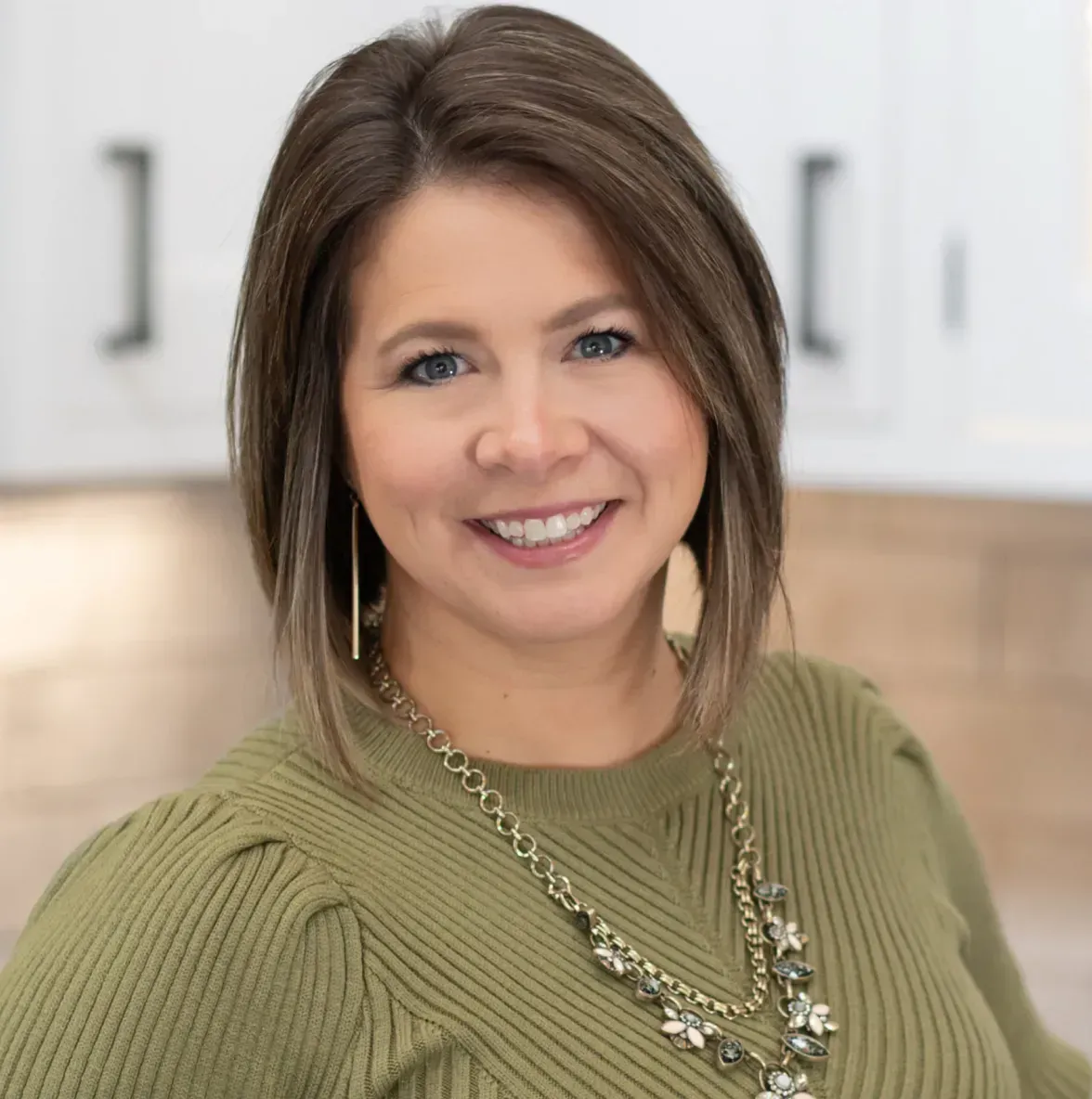 A woman in a blue and white shirt is smiling for the camera.