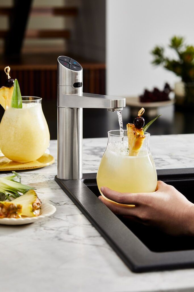A person is pouring a drink into a glass from a faucet.