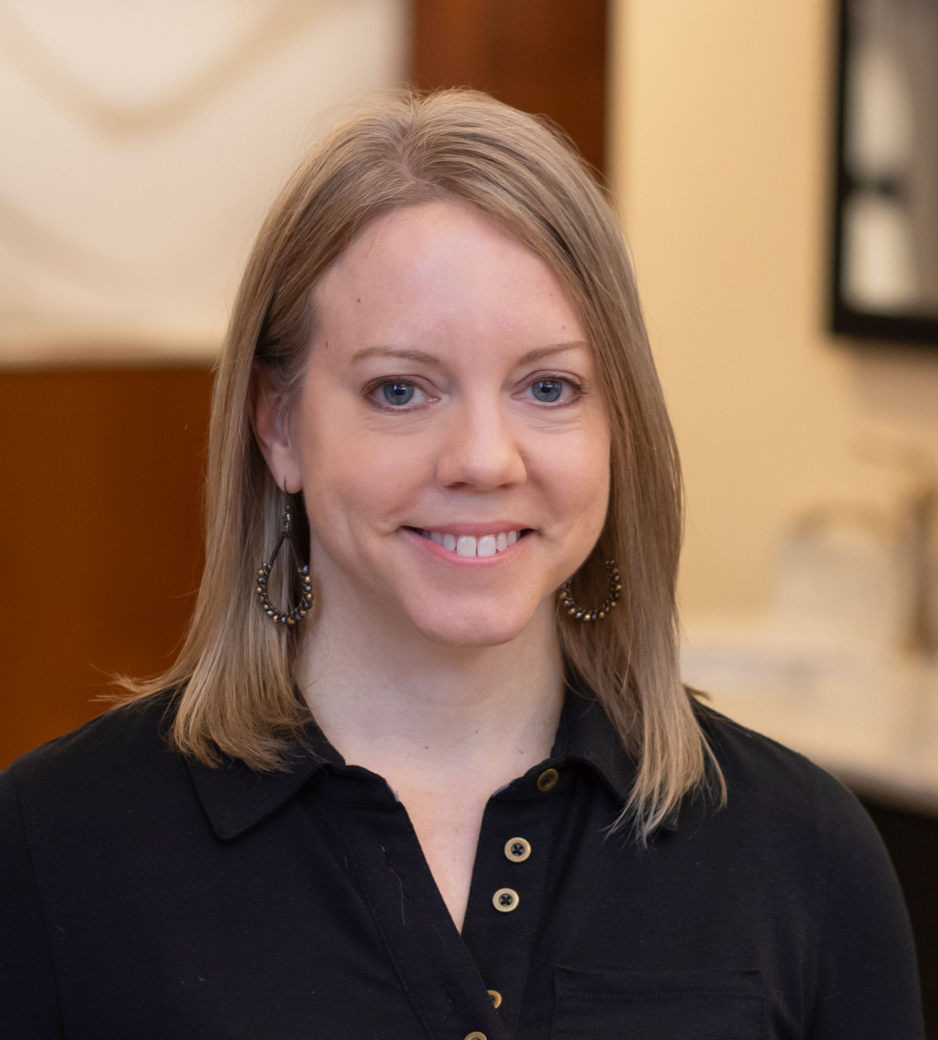A woman in a blue and white shirt is smiling for the camera.