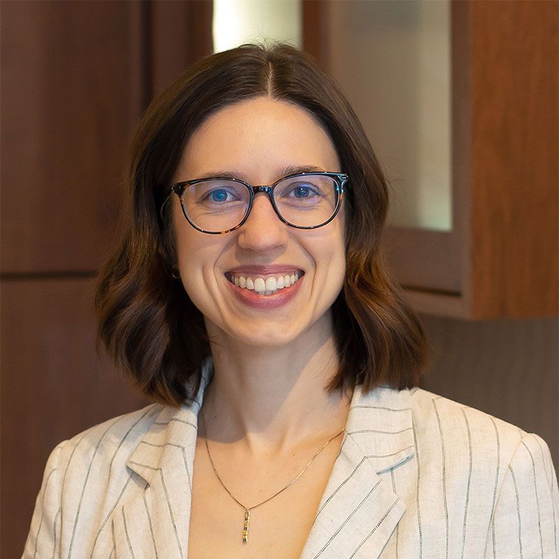 A woman in a blue and white shirt is smiling for the camera.