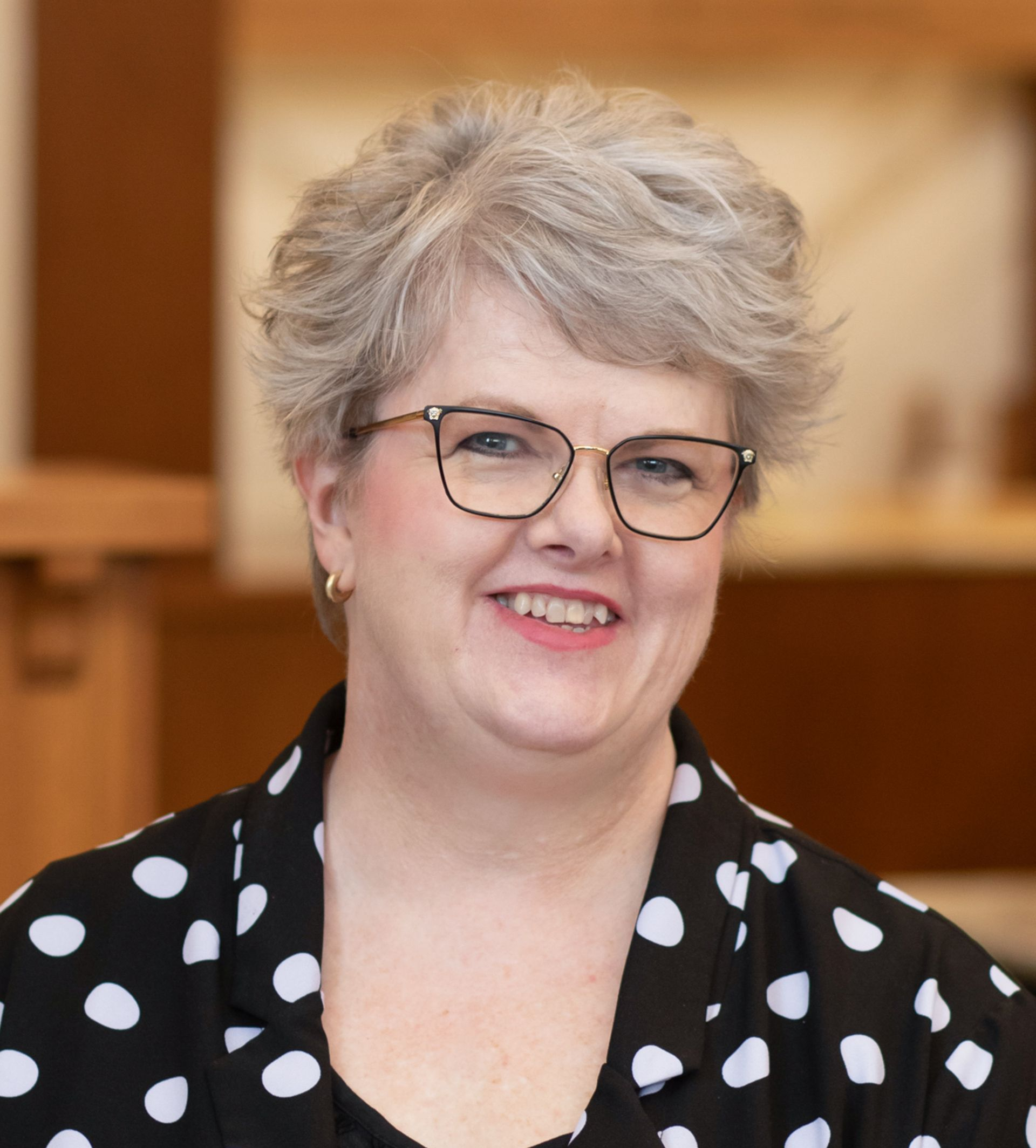 A woman in a blue and white shirt is smiling for the camera.