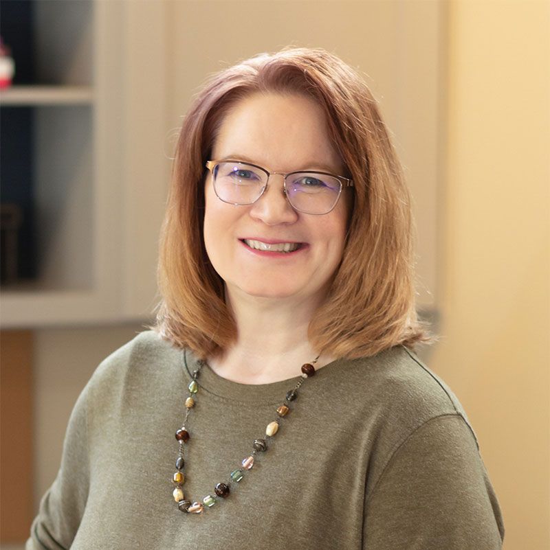 A woman in a blue and white shirt is smiling for the camera.