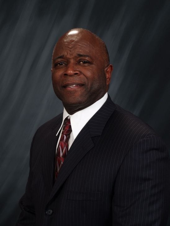 A woman is sitting at a desk with a laptop and a vase of flowers.