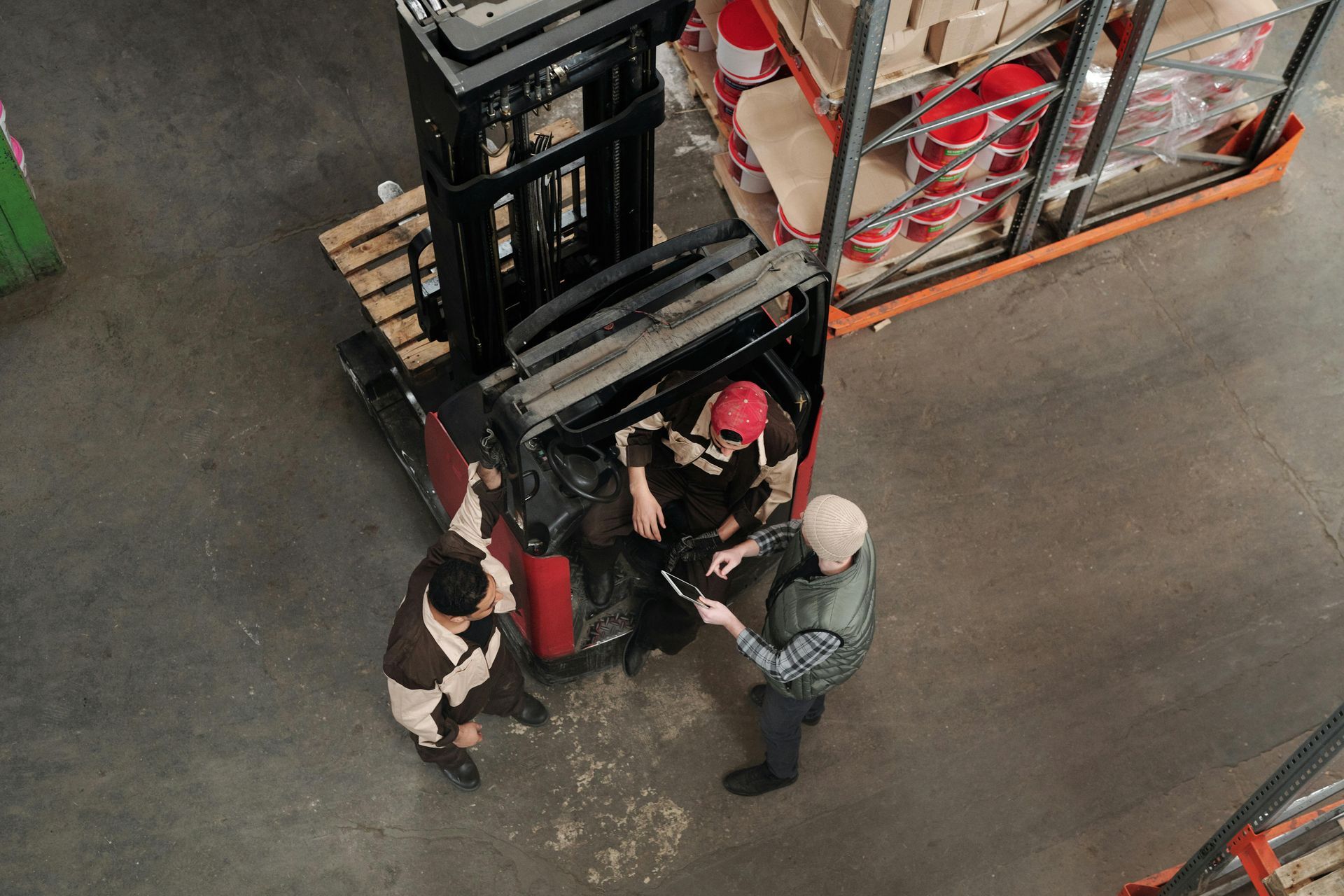 A group of people are standing around a forklift in a warehouse.