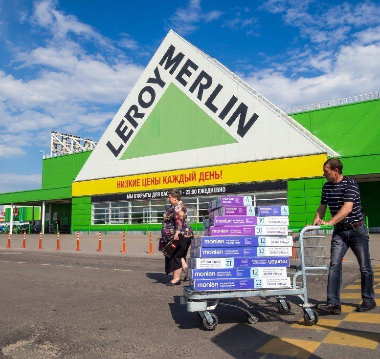 A man pushing a cart with boxes in front of a leroy merlin store