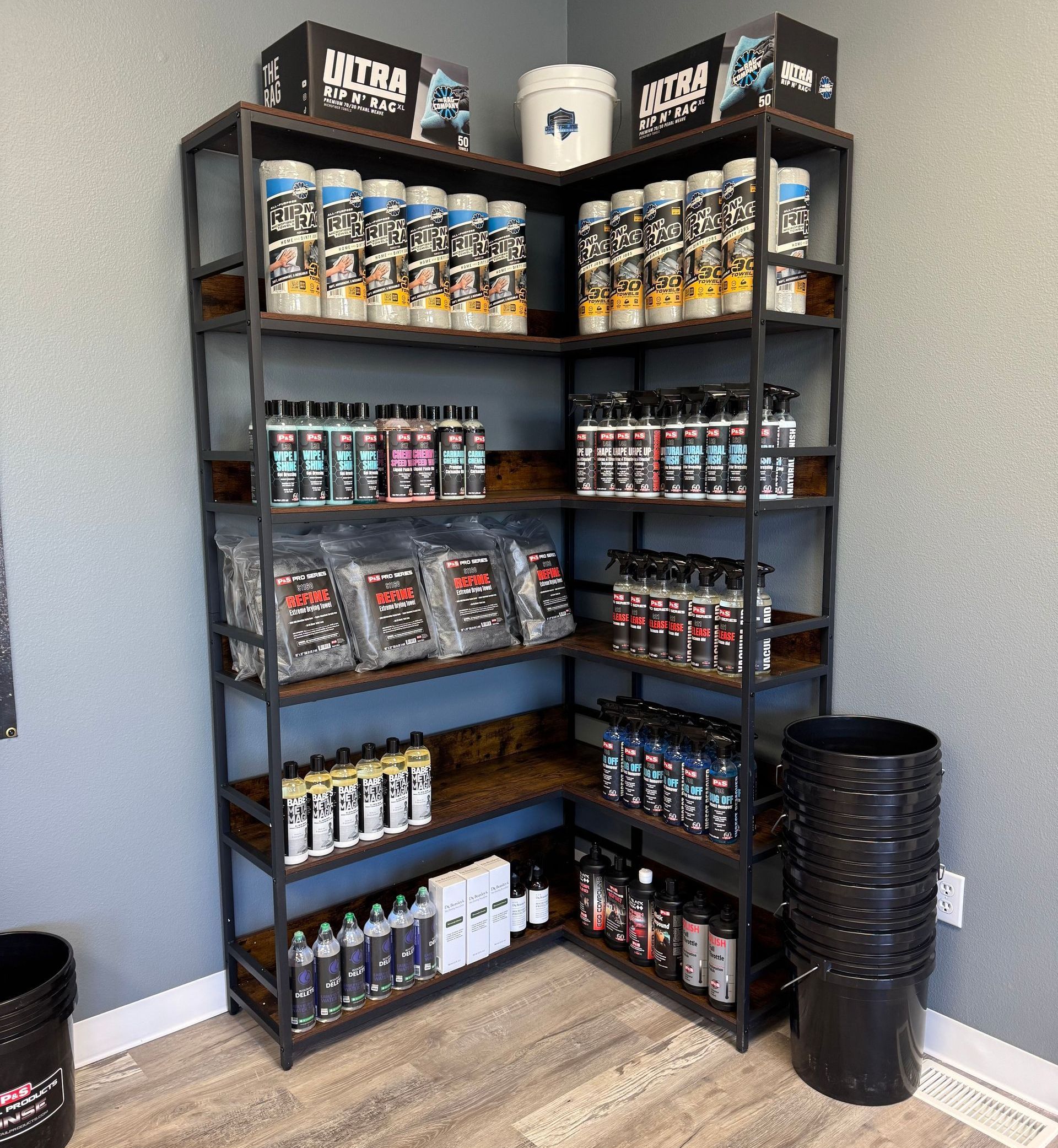 A corner of a room with shelves filled with bottles and buckets.