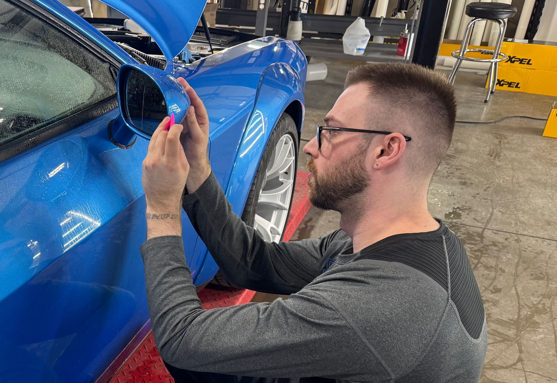 A man is working on a blue car in a garage.