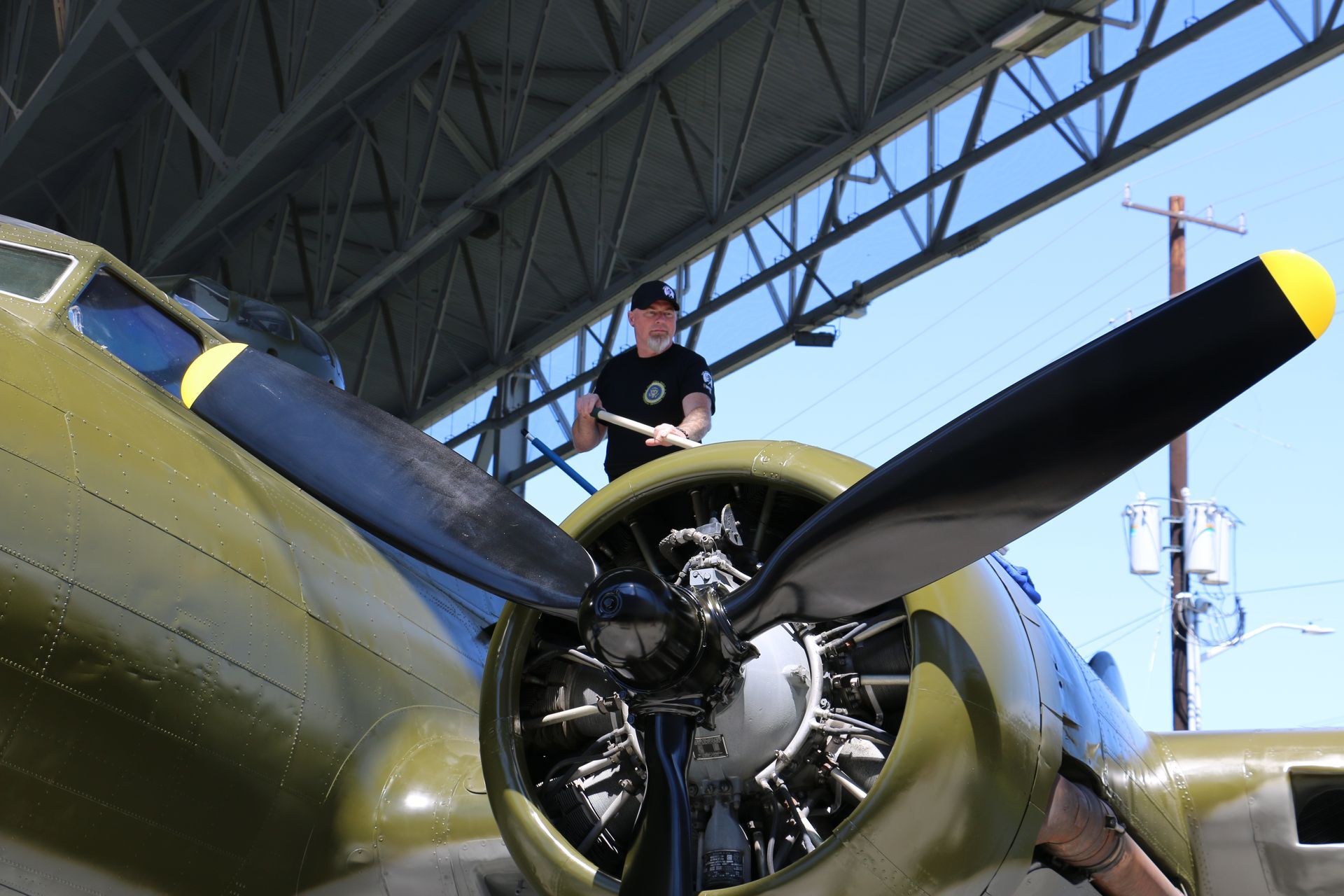 A man is standing on top of a plane in a hangar.