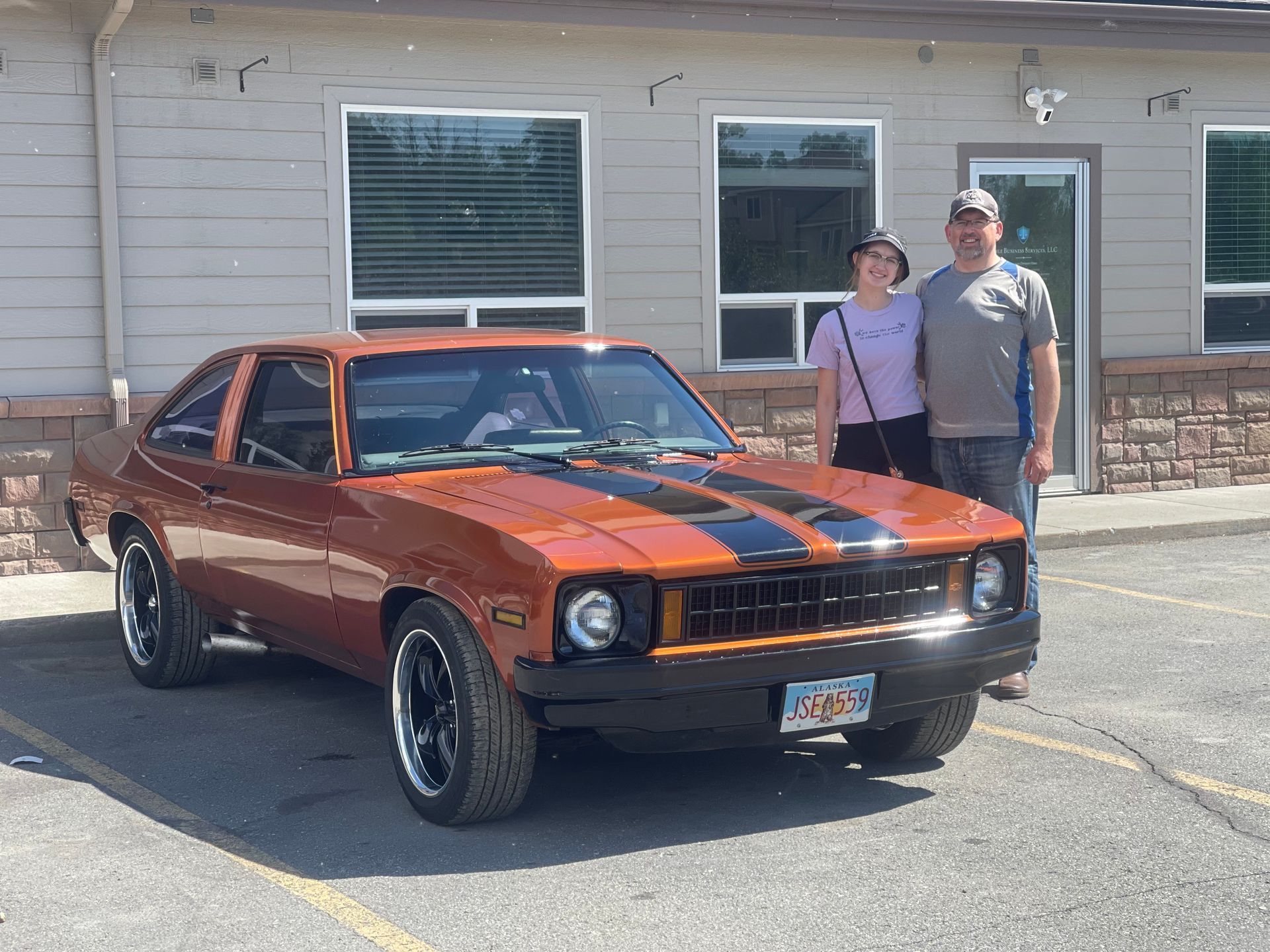 A man with tattoos is polishing a car with a machine.
