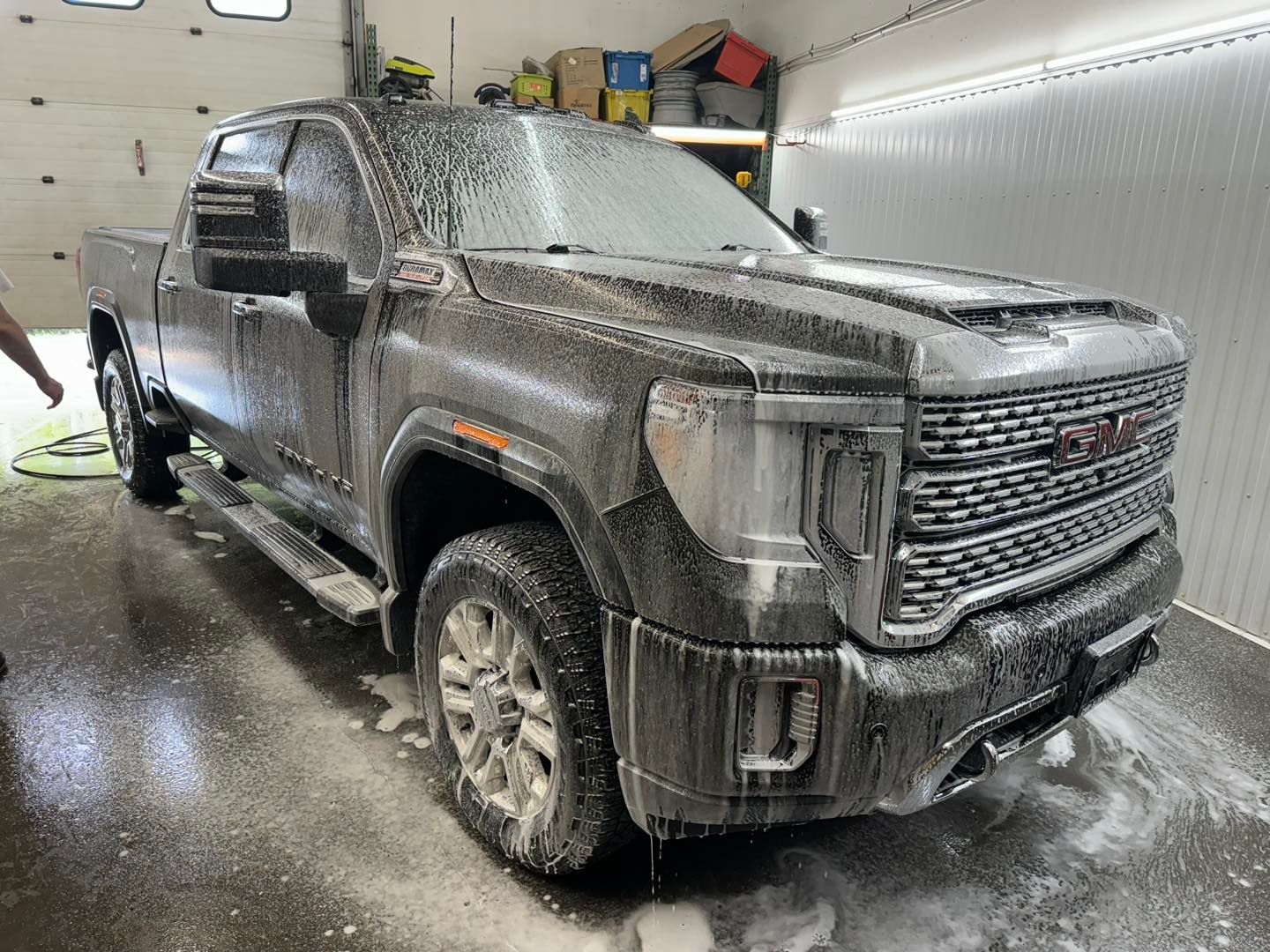 A dirty truck is sitting in a garage covered in foam.