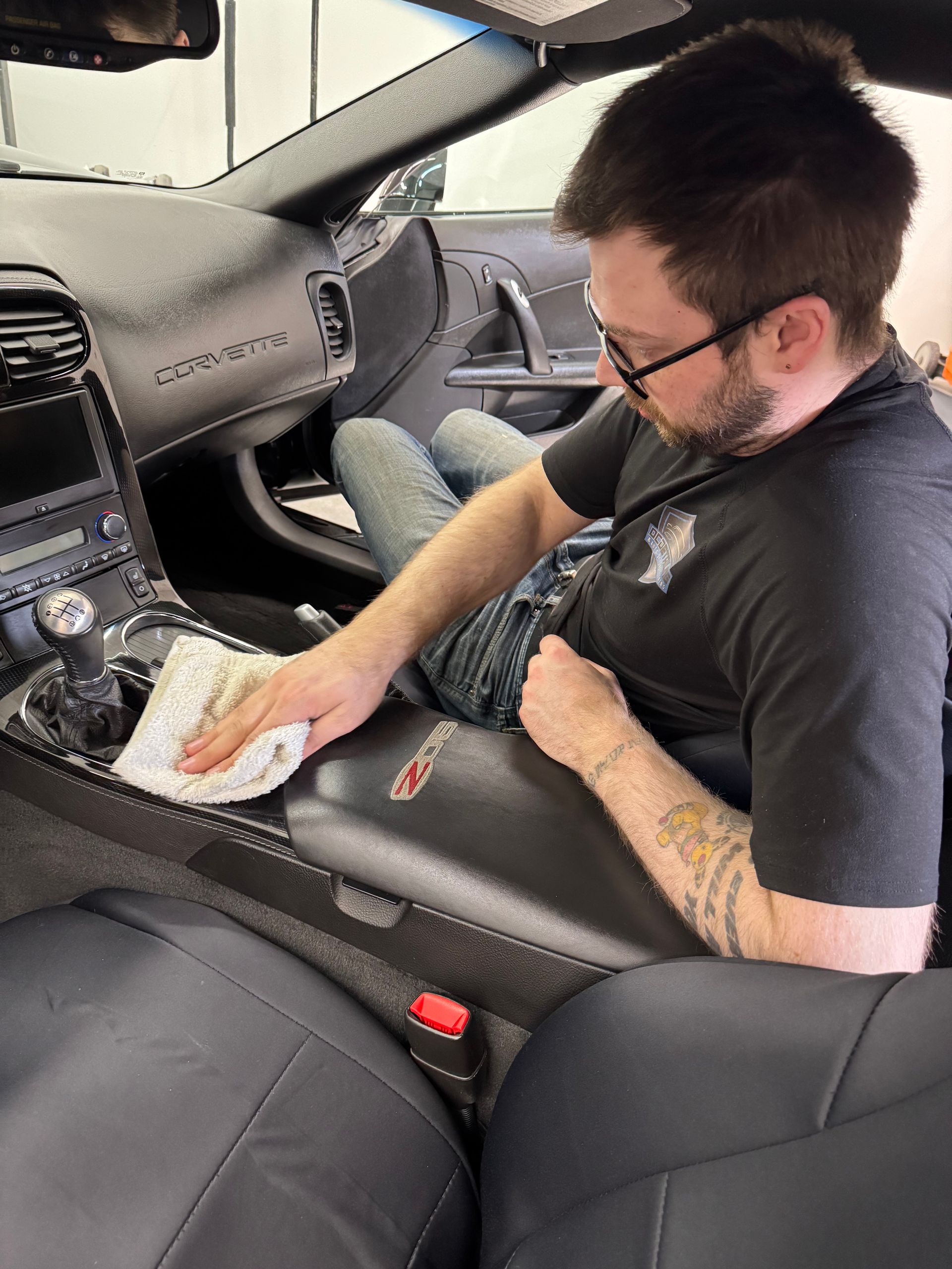 A man is kneeling down next to a motorcycle in a field.