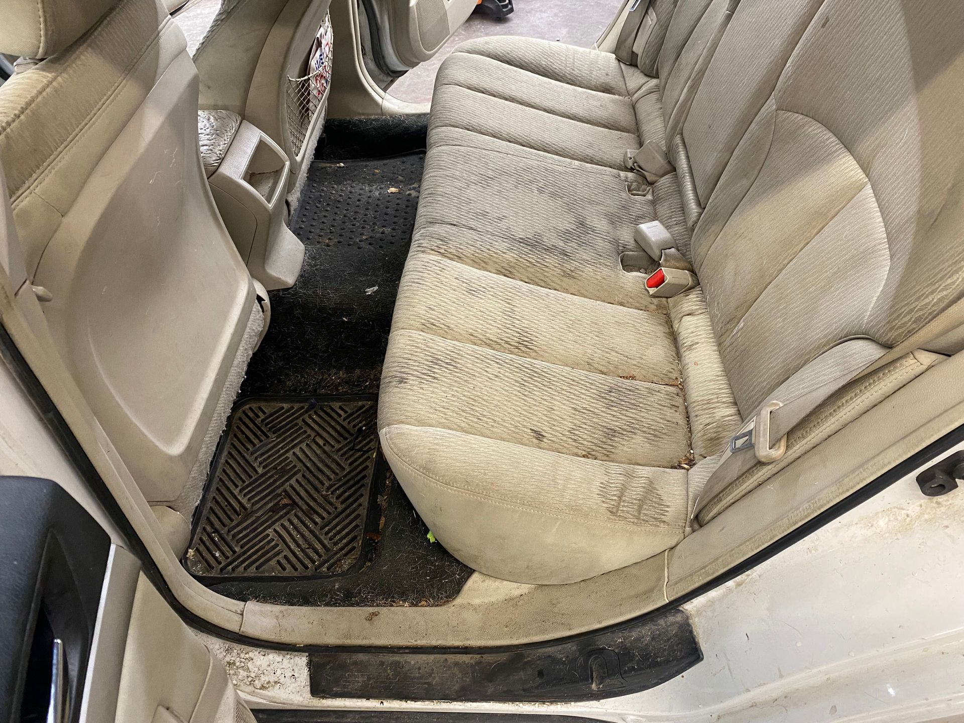 The back seat of a car is dirty and needs to be cleaned.
