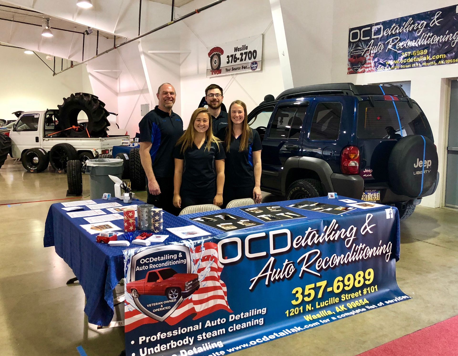 A group of people standing around a table in front of a jeep.