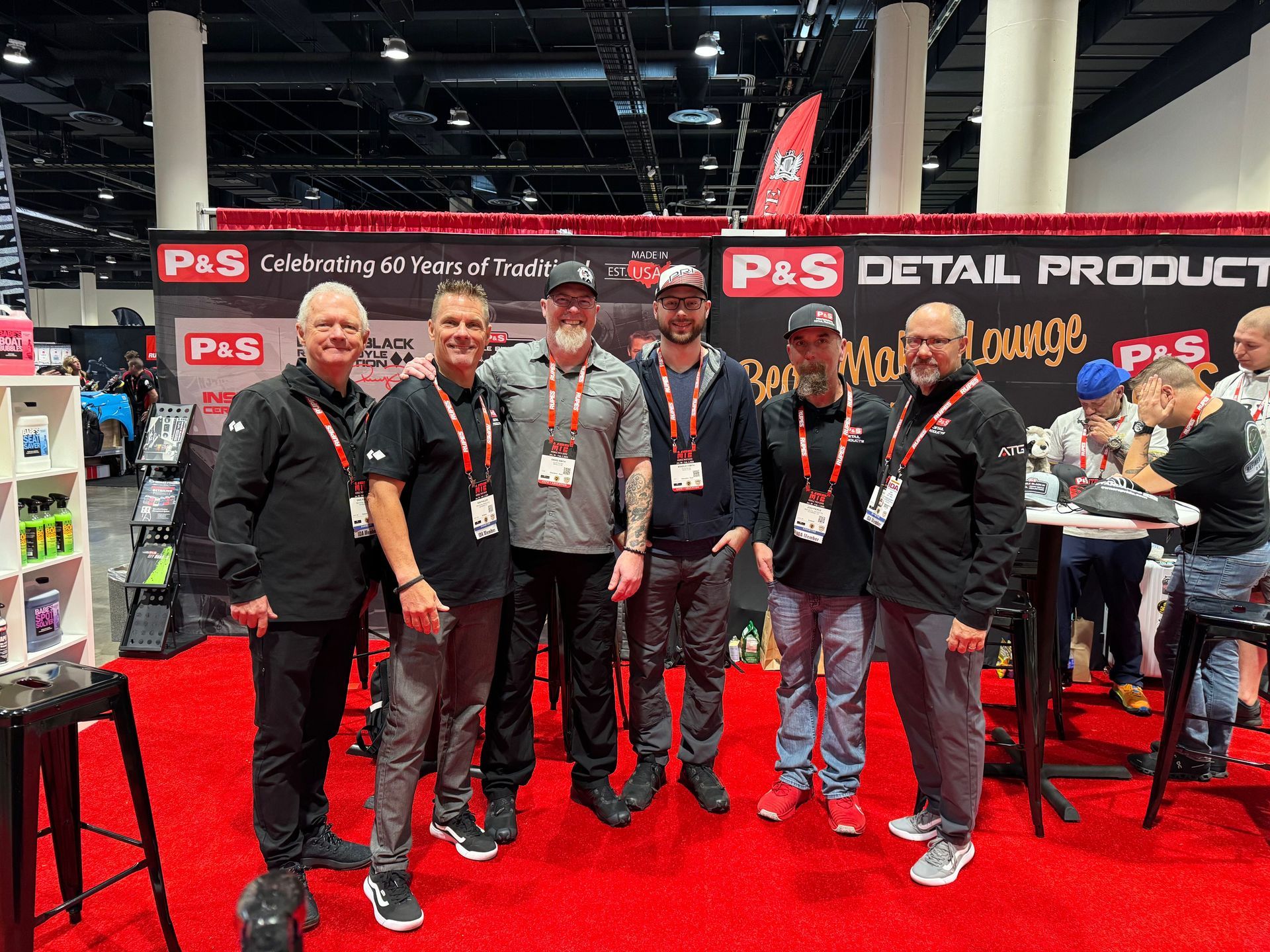 A group of men are posing for a picture at a car show.