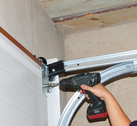 a person is using a drill to fix a garage door .