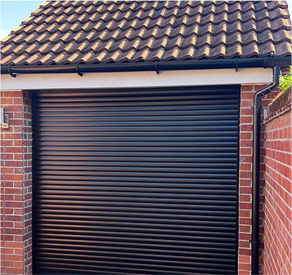 a black garage door with a tiled roof and a brick wall .