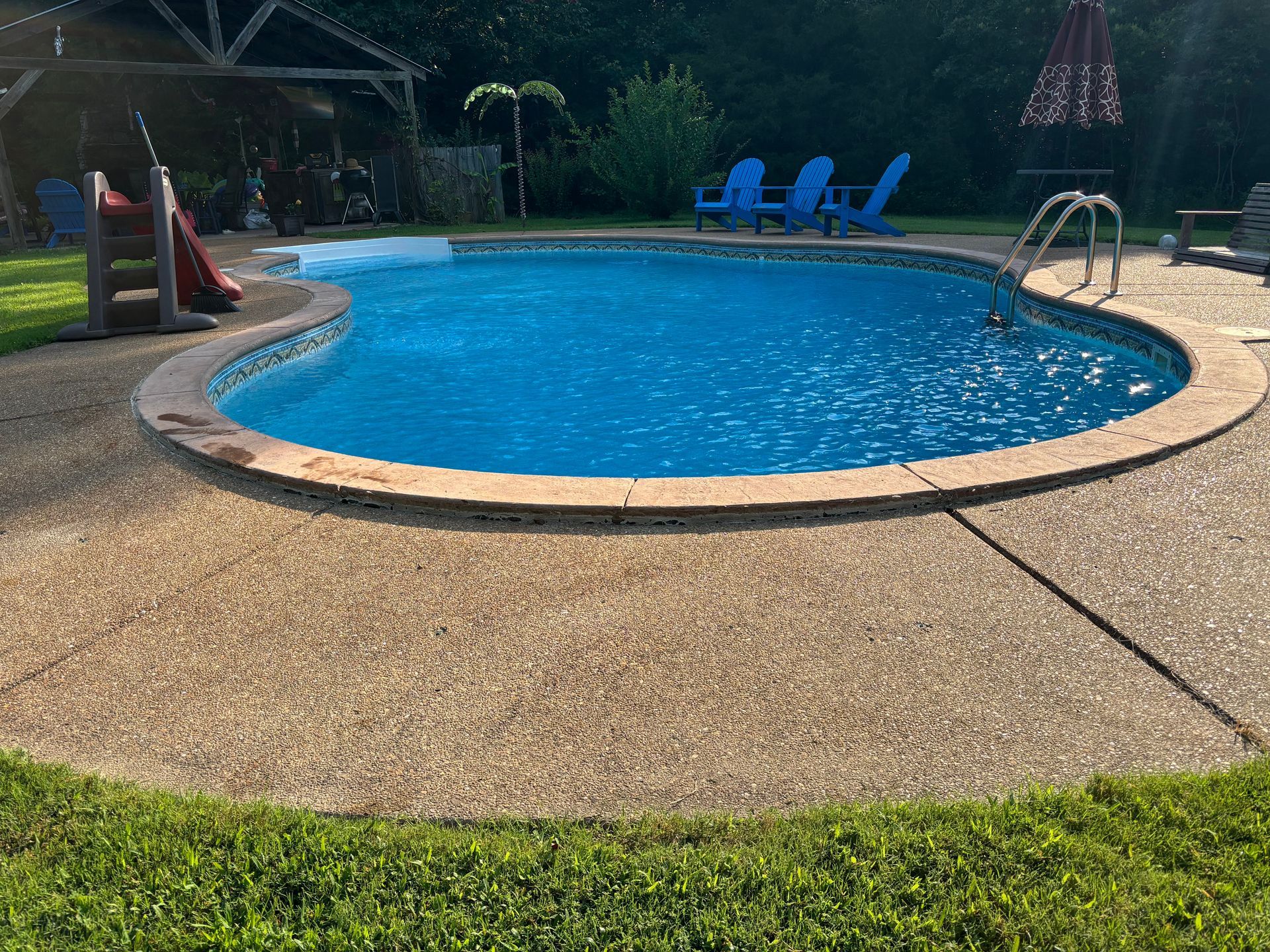 A person uses an electric drill to create a hole in a concrete surface, with a small metal anchor and wrench nearby.