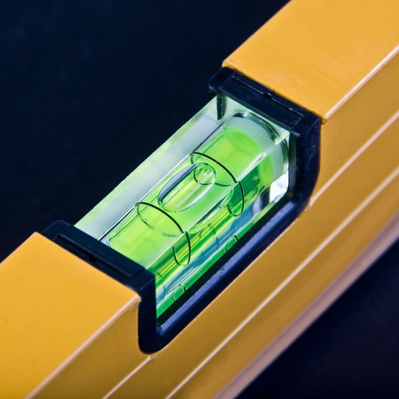 A close-up of a yellow spirit level showing a green vial with an air bubble centered between two black lines.