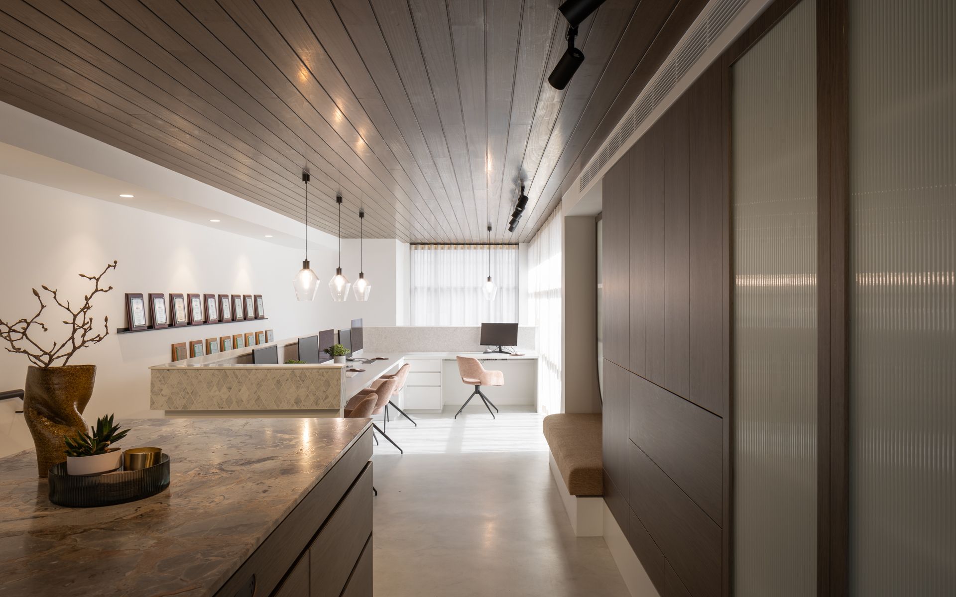 Modern office interior with light wood ceiling, long countertops, desks, and neutral tones. — Goode By Design in Unanderra, NSW