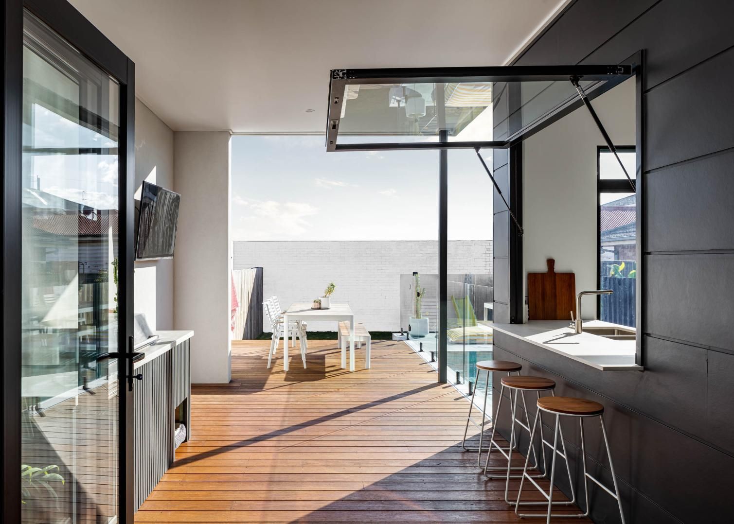 A Kitchen with A Table and Stools and A View of A Pool — Goode By Design in Unanderra, NSW