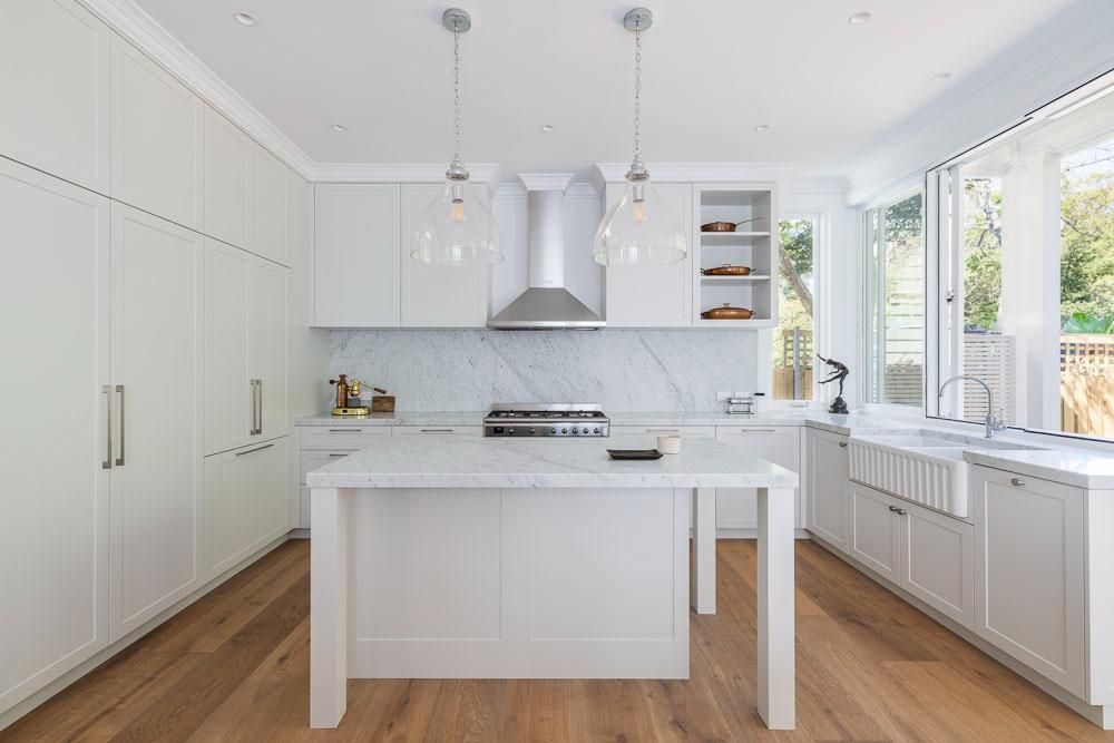 A Kitchen with White Cabinets and A Large Island in The Middle — Goode By Design in Unanderra, NSW