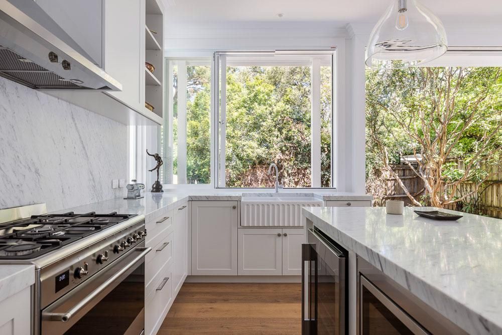 A Kitchen with White Cabinets, a Stove, a Sink, and A Large Window — Goode By Design in Unanderra, NSW
