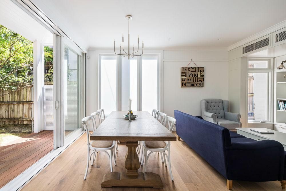 A Dining Room with A Long Table and Chairs and A Blue Couch — Goode By Design in Unanderra, NSW