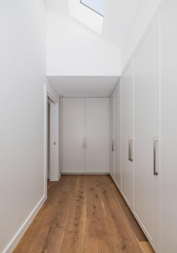 A Long Hallway with Wooden Floors and White Cabinets — Goode By Design in Unanderra, NSW