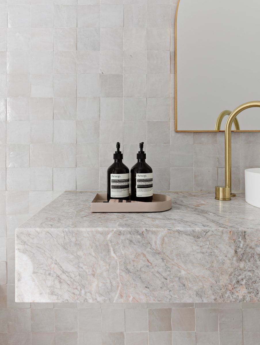 Bathroom With Marble Vanity, Gold Fixtures, and Black Soap Bottles — Goode By Design in Unanderra, NSW