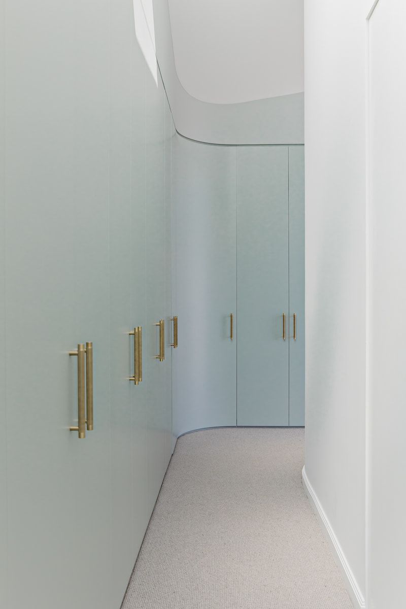 Light Blue Curved Closet Wall With Gold Handles in a Hallway With Carpet — Goode By Design in Unanderra, NSW