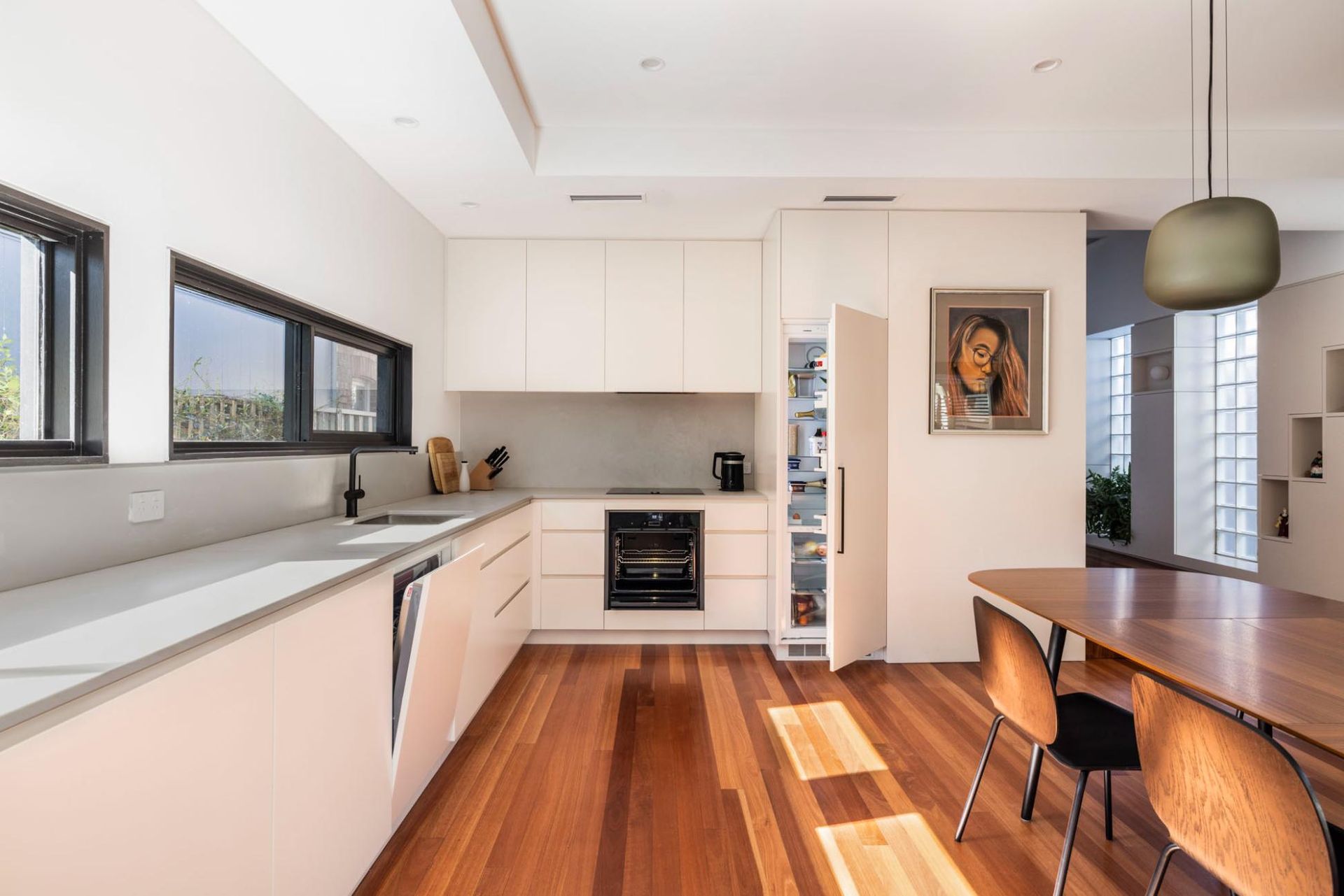 A Kitchen with White Cabinets, Wooden Floors, a Table and Chairs — Goode By Design in Unanderra, NSW