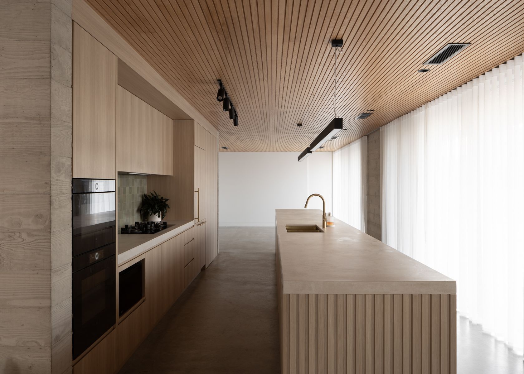 Modern kitchen with wood ceiling and cabinetry, long island with sink, and sheer curtains.